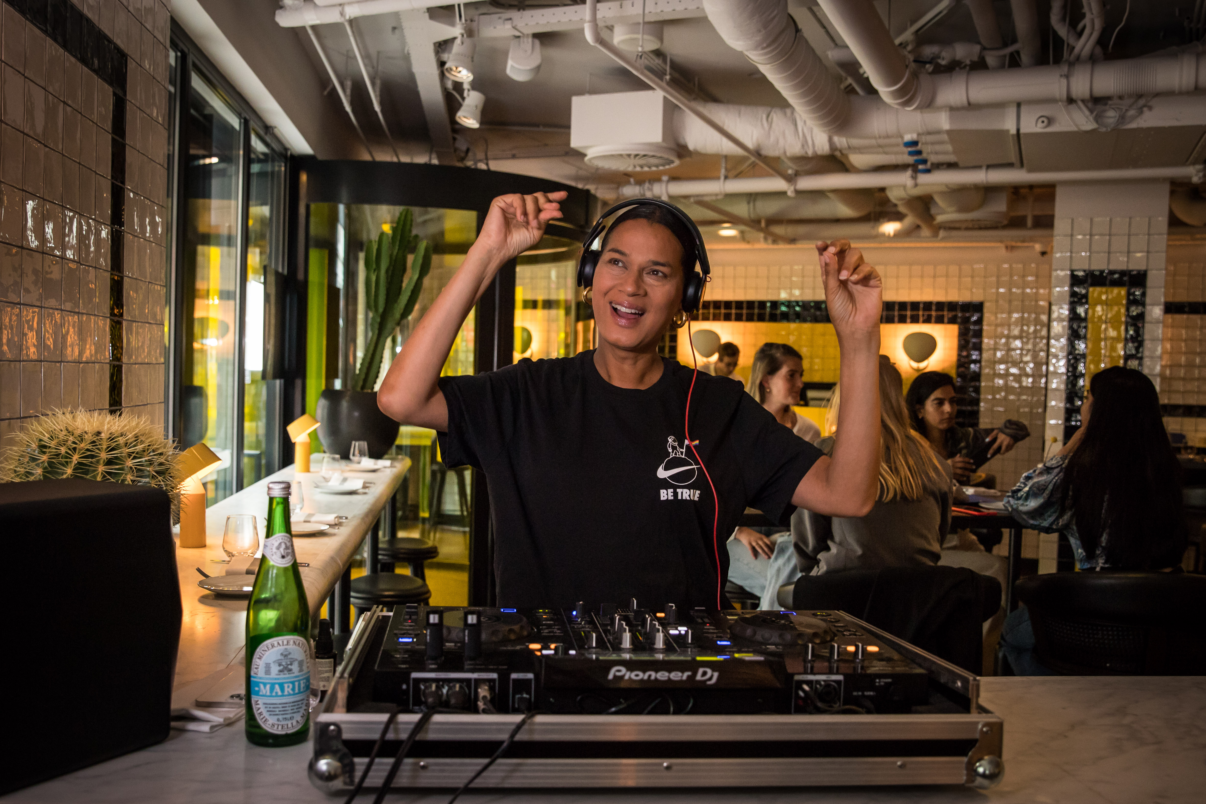 A DJ in headphones spins music, creating a lively atmosphere in Celia's vibrant setting for DJ Fridays in Amsterdam.