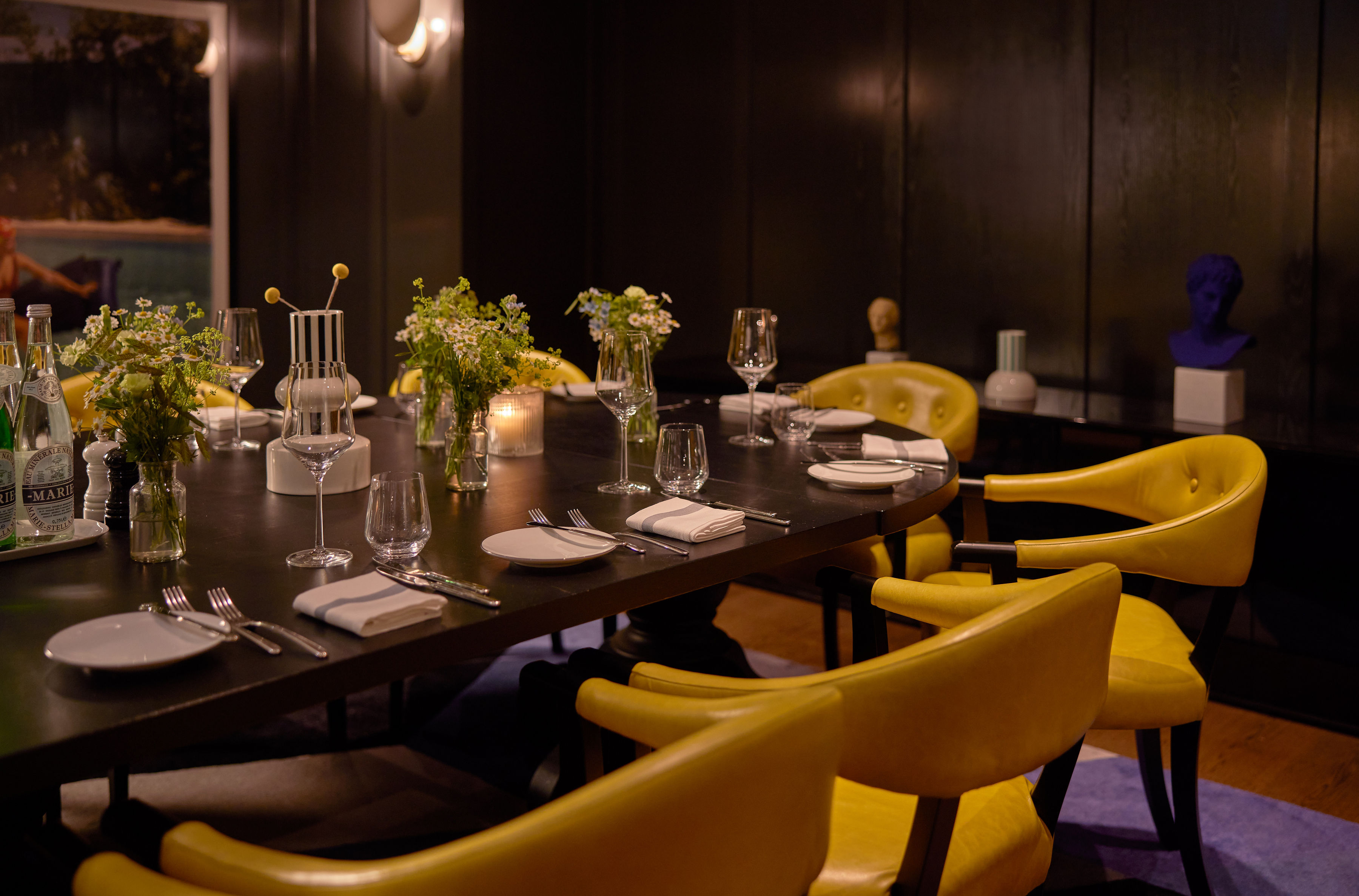 A person in denim clothes working on a laptop at a table with a coffee cup and muffin, in a stylish café setting at Celia.
