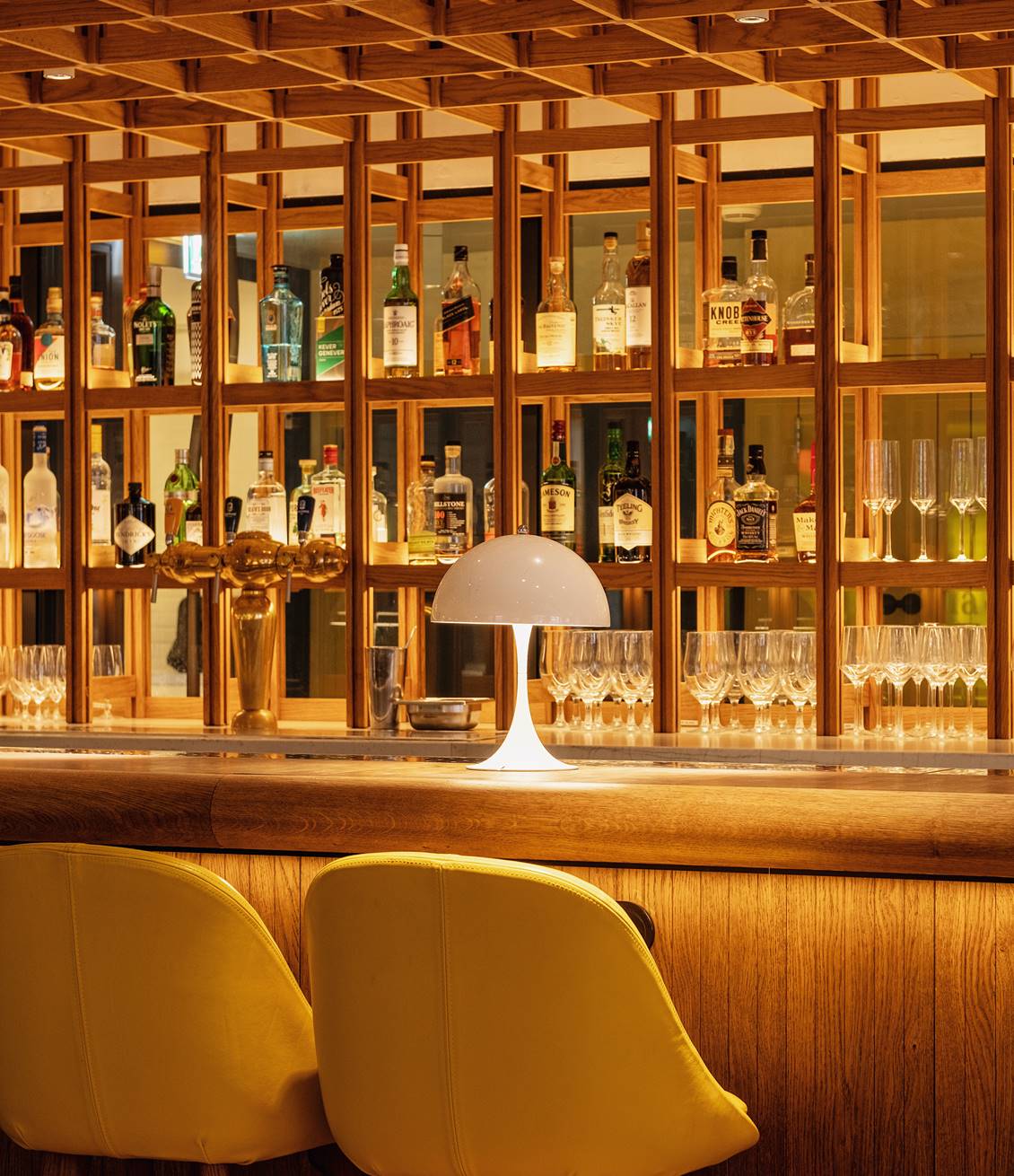 A bar scene with shelves of bottles and glassware, illuminated by soft lighting at the elegant Celia Amsterdam.