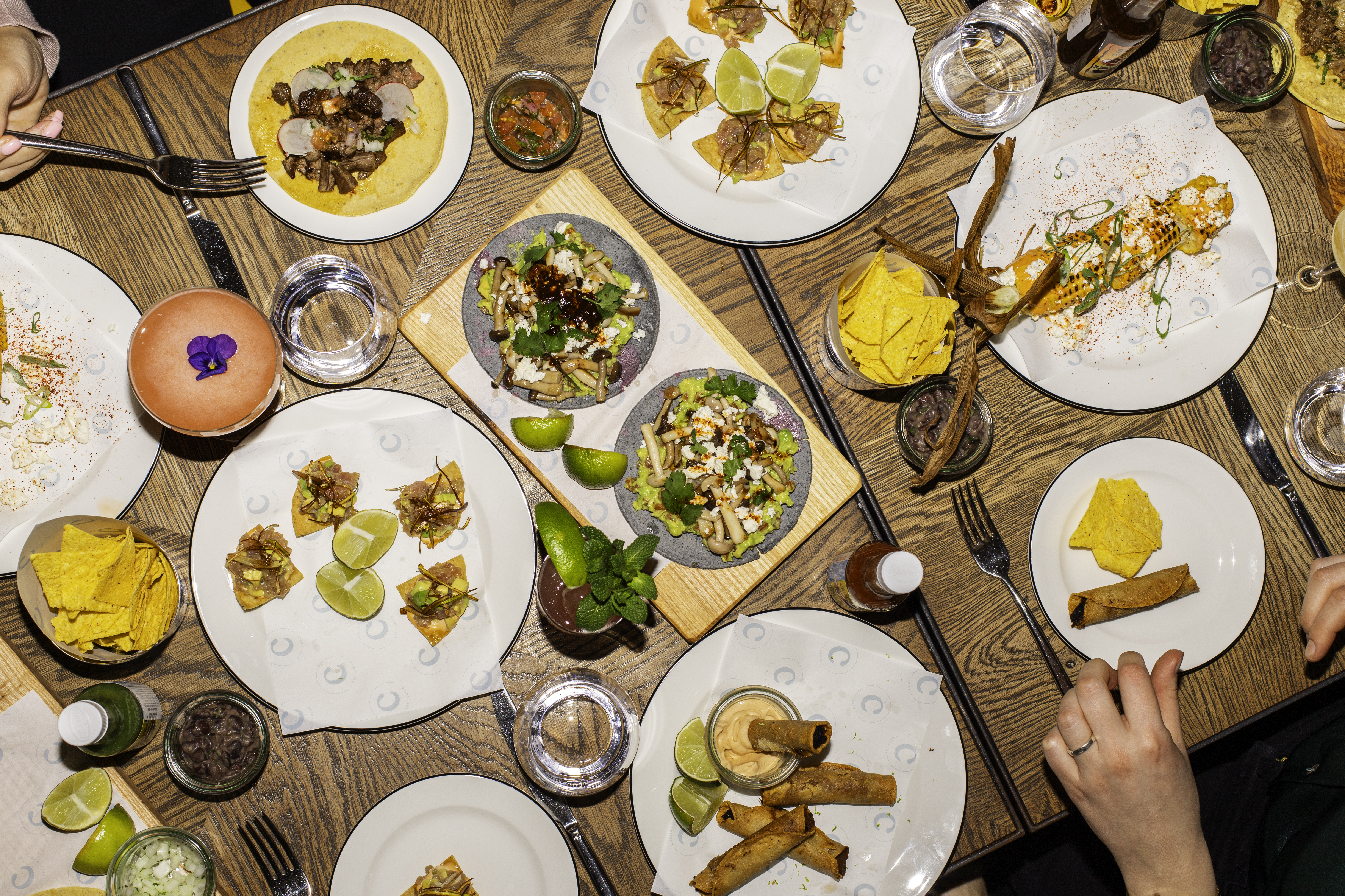 A table rich with food, featuring a roasted chicken, vegetables, and side dishes set for a boozy brunch at Celia Amsterdam.